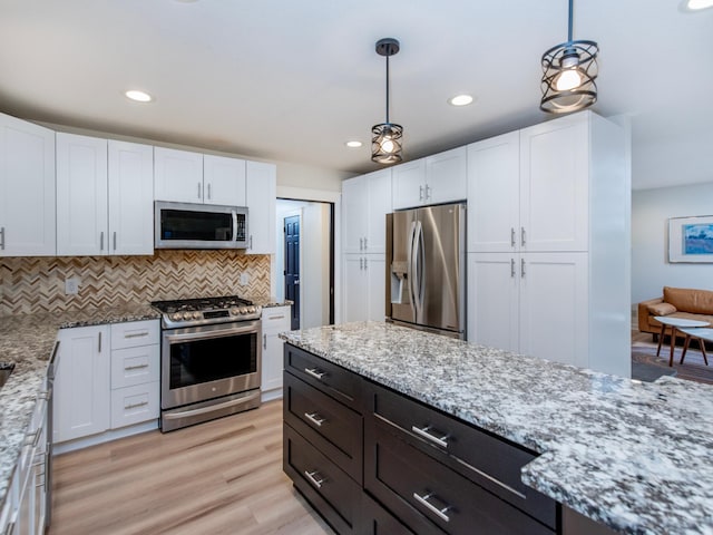 2415 Edgerton St, Little Canada, MN 55117 - kitchen with stainless steel appliances, white cabinetry, light stone countertops, backsplash, and hanging light fixtures