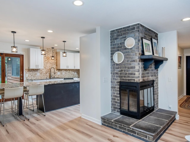 2415 Edgerton St, Little Canada, MN 55117 - kitchen featuring white cabinetry, a sink, light wood finished floors, backsplash, and recessed lighting