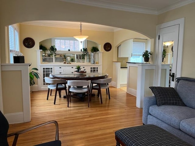 dining area with crown molding, baseboards, light wood-style floors, and a wealth of natural light