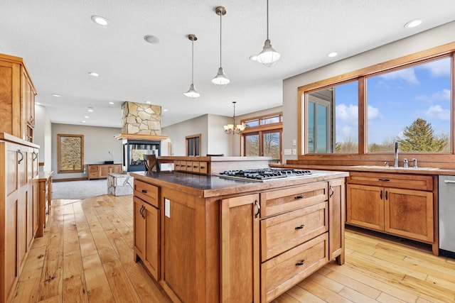 206 Fairway Cir, Glencoe, MN 55336 - kitchen with appliances with stainless steel finishes, light wood finished floors, a stone fireplace, a center island, and pendant lighting