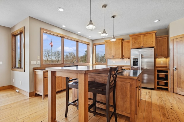 206 Fairway Cir, Glencoe, MN 55336 - kitchen with stainless steel fridge, brown cabinets, light wood-style flooring, decorative light fixtures, and recessed lighting