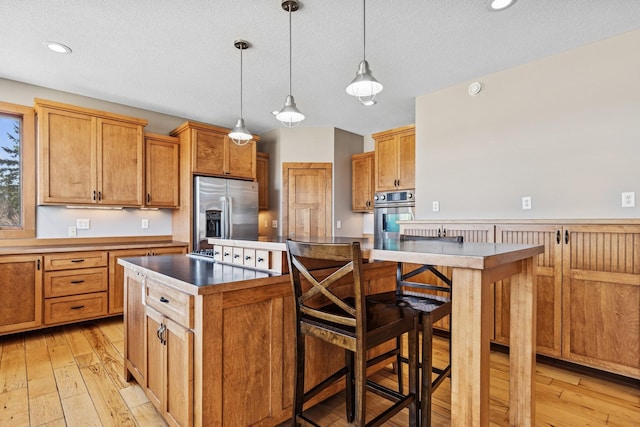 206 Fairway Cir, Glencoe, MN 55336 - kitchen with stainless steel appliances, light wood finished floors, a kitchen island, decorative light fixtures, and a textured ceiling