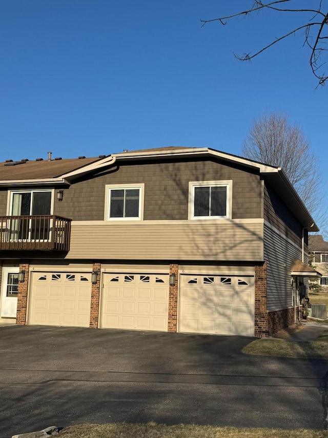 view of front of home with an attached garage, aphalt driveway, and brick siding
