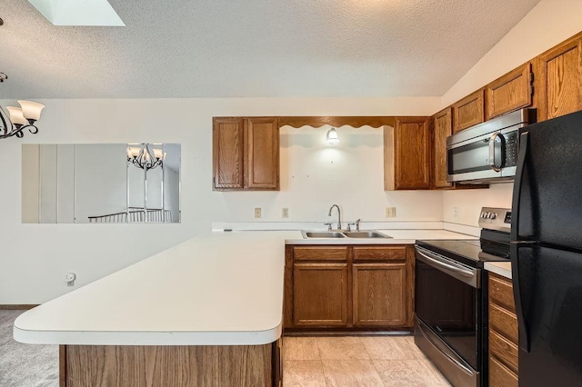 kitchen featuring brown cabinetry, appliances with stainless steel finishes, a sink, light countertops, and a peninsula