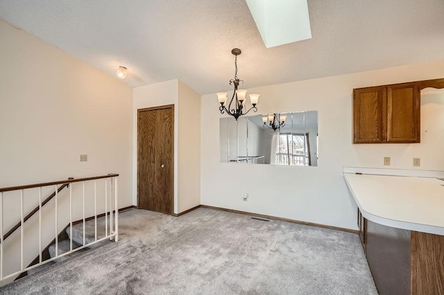 interior space with light colored carpet, a skylight, an inviting chandelier, and baseboards
