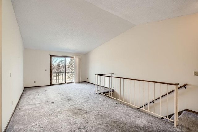 carpeted empty room featuring baseboards, a textured ceiling, and lofted ceiling