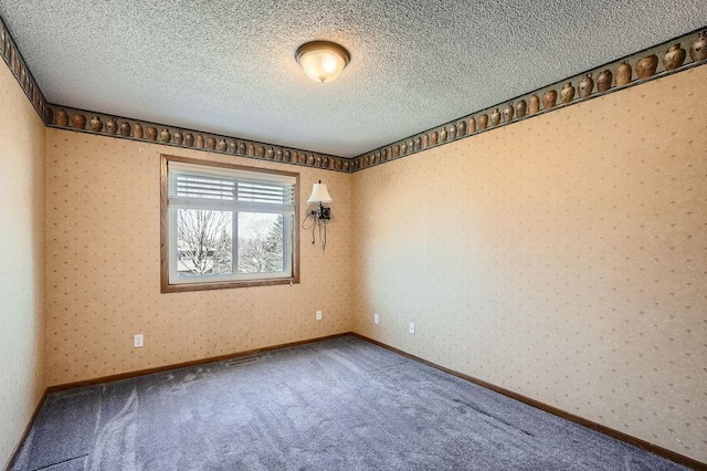 carpeted spare room with a textured ceiling and wallpapered walls