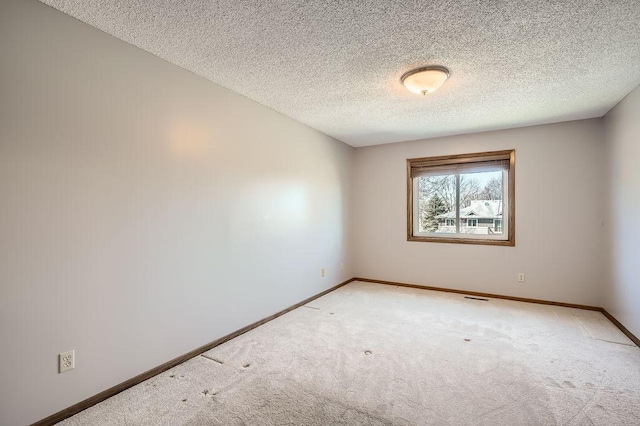 empty room featuring a textured ceiling, baseboards, light colored carpet, and visible vents