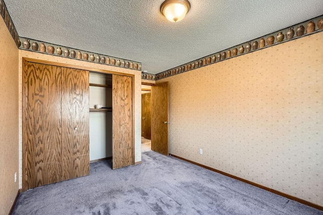 unfurnished bedroom with a closet, carpet flooring, wallpapered walls, and a textured ceiling