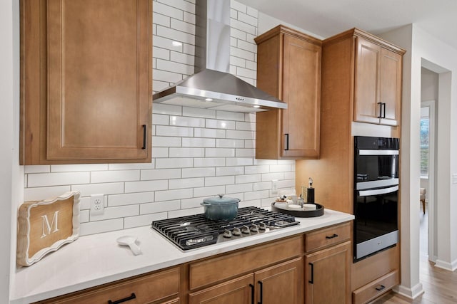 10054 Mulberry Ln, Corcoran, MN 55374 - kitchen with light countertops, double wall oven, wall chimney range hood, stainless steel gas stovetop, and tasteful backsplash