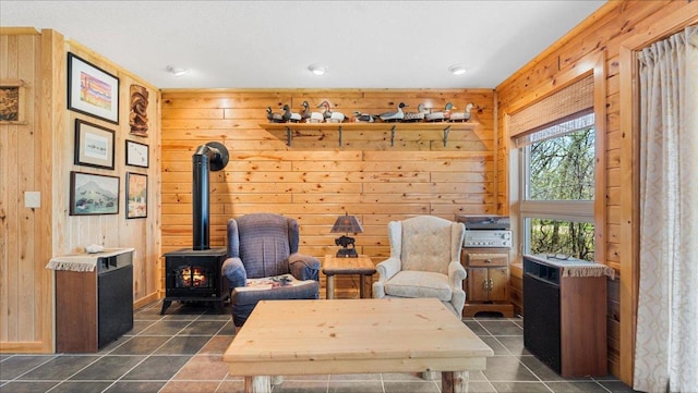 living area with a wood stove, wooden walls, and dark tile patterned floors
