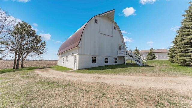 view of side of home with a barn, an outbuilding, stairway, a gambrel roof, and a yard