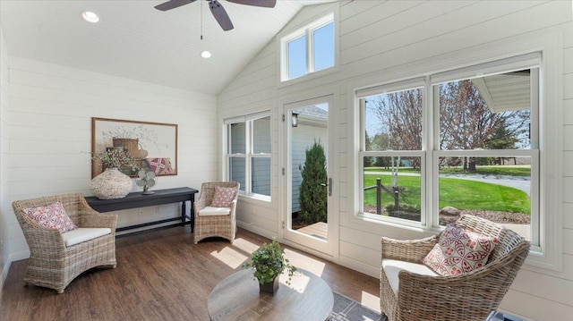 sunroom featuring a ceiling fan, wood finished floors, wooden walls, and high vaulted ceiling
