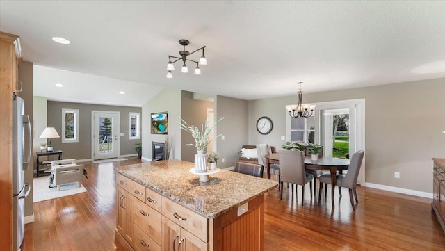kitchen featuring a chandelier, wood finished floors, baseboards, freestanding refrigerator, and open floor plan