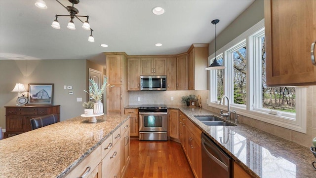 kitchen featuring a sink, decorative backsplash, light stone countertops, and stainless steel appliances