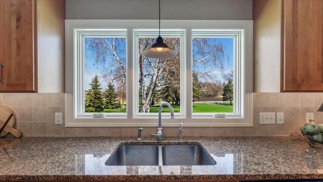 kitchen with a sink, backsplash, and dark stone countertops