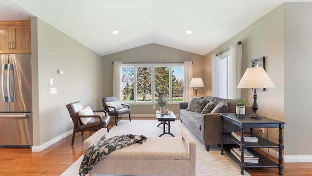 living area featuring baseboards, light wood finished floors, and lofted ceiling