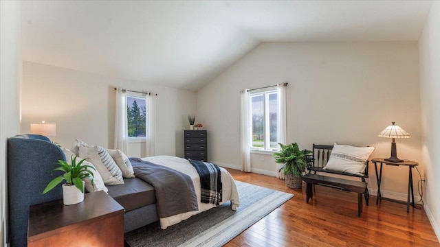 bedroom with baseboards, wood finished floors, and multiple windows