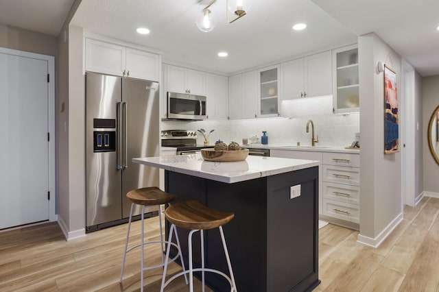4075 51st St Unit 302, Edina, MN 55424 - kitchen featuring stainless steel appliances, a sink, a kitchen island, light wood-style flooring, and baseboards