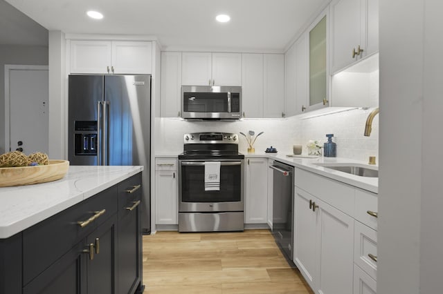 4075 51st St Unit 302, Edina, MN 55424 - kitchen with stainless steel appliances, a sink, white cabinets, recessed lighting, and backsplash