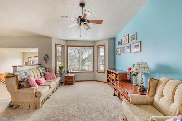 living area featuring carpet flooring, a textured ceiling, a ceiling fan, and a wealth of natural light