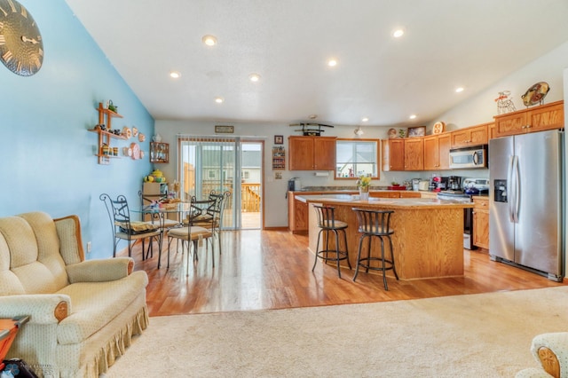 kitchen featuring recessed lighting, appliances with stainless steel finishes, a kitchen island, and a breakfast bar