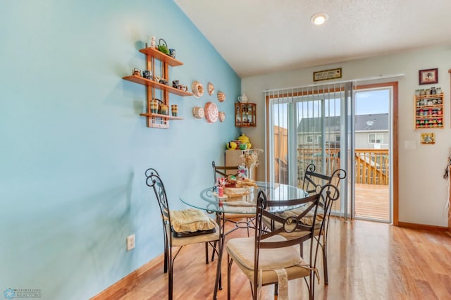 dining room with baseboards, vaulted ceiling, and light wood-type flooring