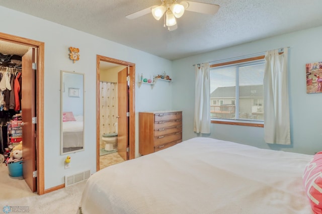 carpeted bedroom with visible vents, a textured ceiling, a walk in closet, and a closet