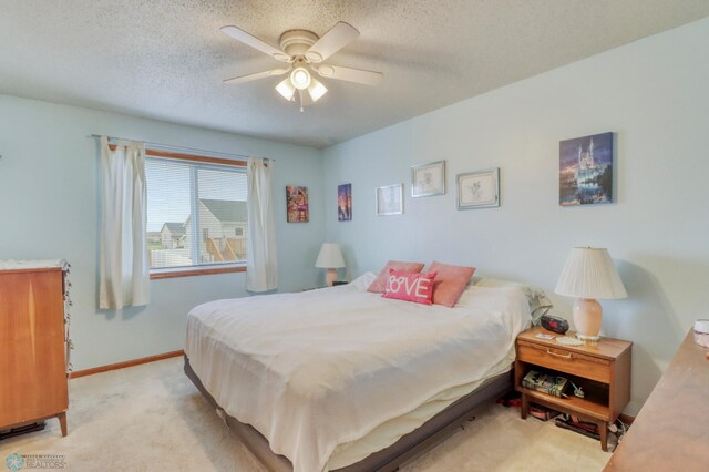 bedroom featuring baseboards, light carpet, a ceiling fan, and a textured ceiling
