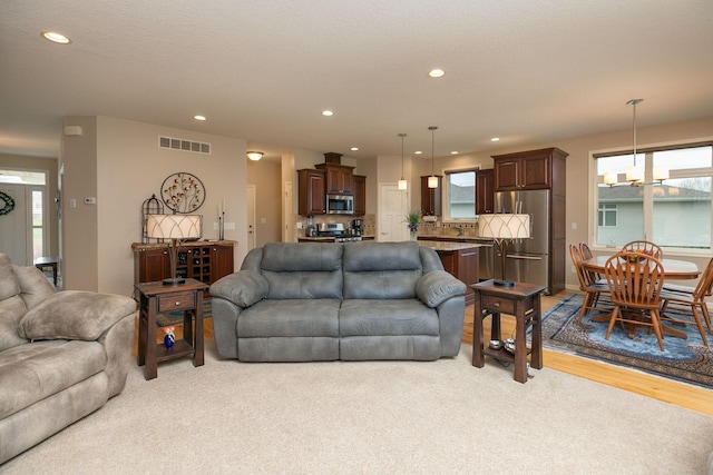 living area with visible vents, recessed lighting, plenty of natural light, and an inviting chandelier