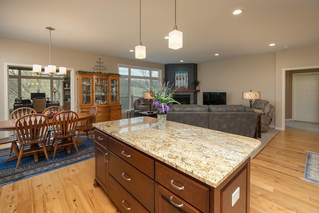 kitchen featuring light wood-type flooring, decorative light fixtures, a fireplace, and a center island