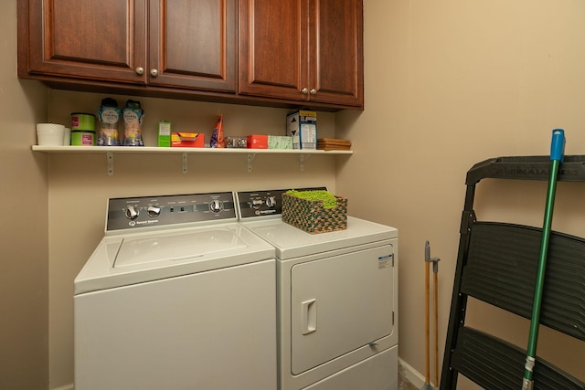 clothes washing area featuring baseboards, cabinet space, and washing machine and clothes dryer