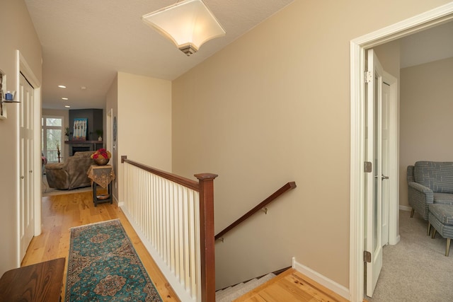 corridor with recessed lighting, baseboards, an upstairs landing, and light wood-style flooring
