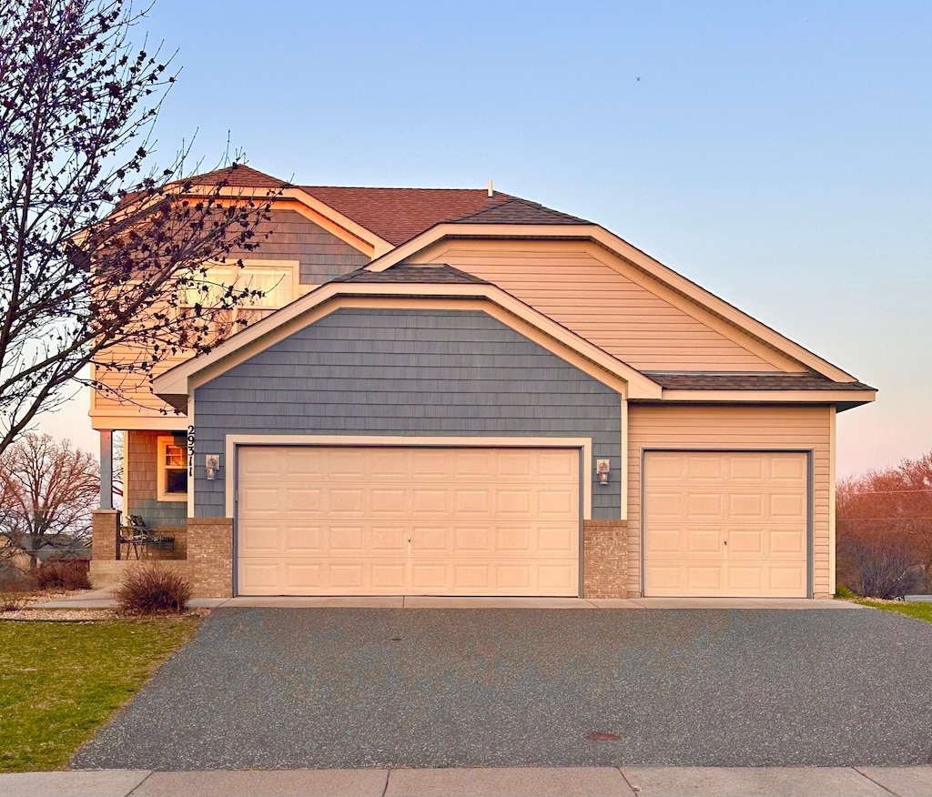 view of front facade with a garage, roof with shingles, and driveway