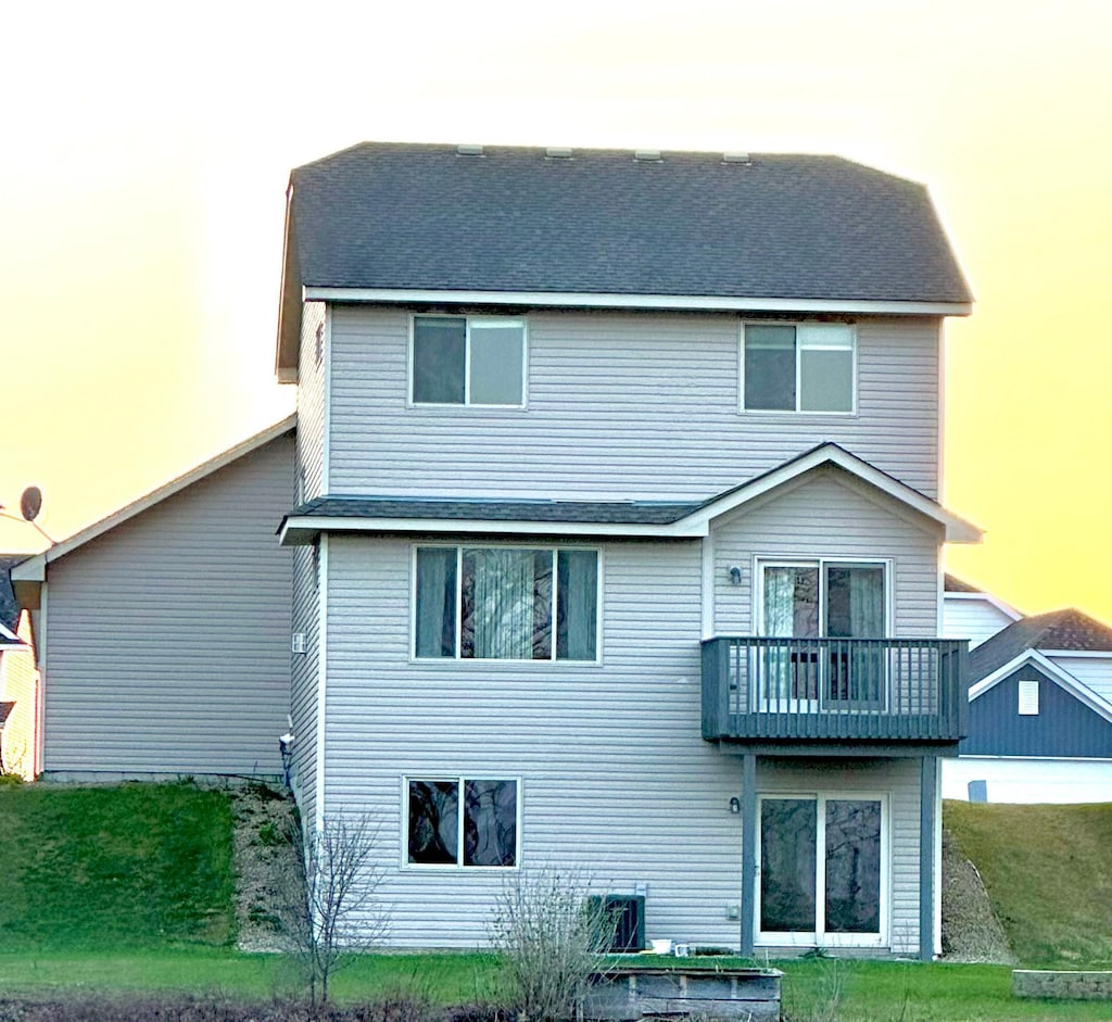 rear view of property with a lawn and a balcony