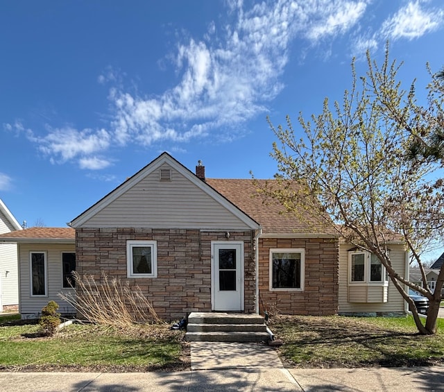 view of front of house featuring a shingled roof, a chimney, and stone siding