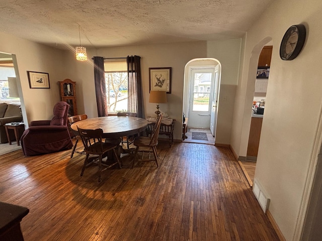 dining area with wood-type flooring, arched walkways, and visible vents