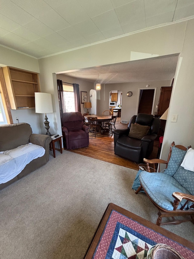 living room featuring visible vents, ornamental molding, carpet, and wood finished floors