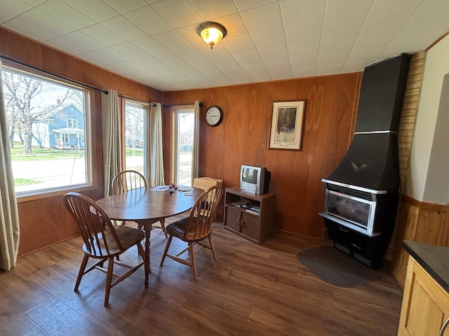 dining space with wood walls and dark wood finished floors