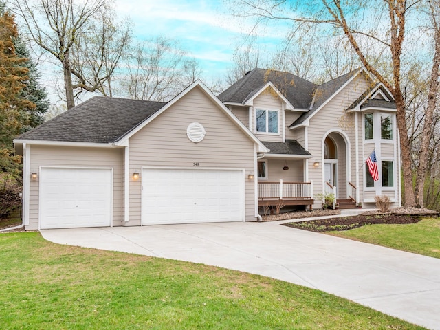 traditional home featuring concrete driveway, an attached garage, a front lawn, and a shingled roof
