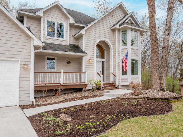 traditional-style home with covered porch, a shingled roof, and a garage