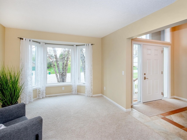 foyer entrance with baseboards and carpet flooring