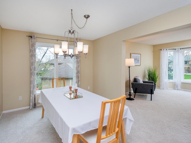 dining room with light colored carpet, baseboards, and a notable chandelier
