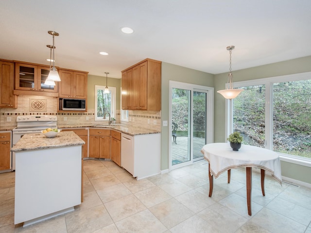 kitchen featuring a sink, white appliances, decorative backsplash, light stone countertops, and hanging light fixtures
