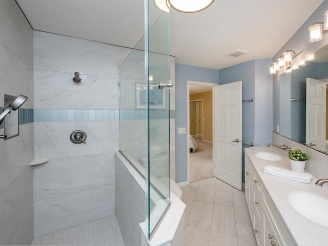 full bath with double vanity, visible vents, tiled shower, and a sink