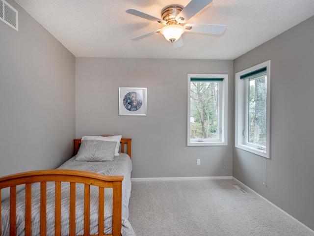 carpeted bedroom with baseboards, ceiling fan, and visible vents
