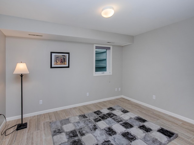empty room featuring light wood-style floors, visible vents, and baseboards
