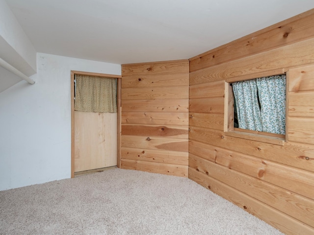 carpeted spare room with wood walls