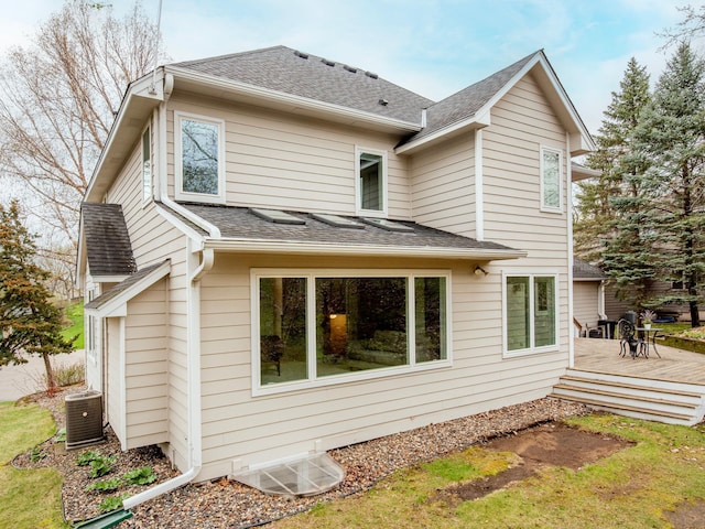 back of property featuring a shingled roof, a deck, and central AC