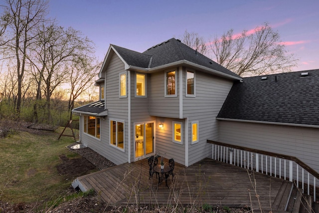 back of property at dusk featuring a shingled roof and a wooden deck